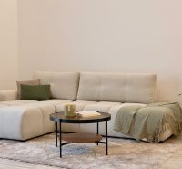 Helles Interieur mit bequemer Couch, Couchtisch und Boden mit Holzdekor.