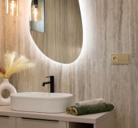 Ein Badezimmer in einem Einfamilienhaus mit einem ovalen Spiegel, einem Waschbecken und Lichtern.