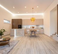 Küche und Wohnzimmer in einem Einfamilienhaus mit dekorativer Leuchte und Boden mit Holzdekor.