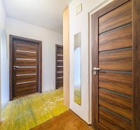 Der Flur in der 3-Zimmer-Wohnung mit Holztüren und einem Boden mit Holzdekor.