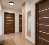 Flur mit Holzboden, Spiegel und skandinavischen Möbeln in einer 3-Zimmer-Wohnung.