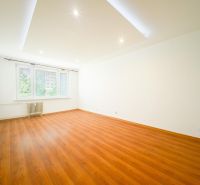 Geräumiges Wohnzimmer mit Holzboden in einer 3-Zimmer-Wohnung, weiße Wände.