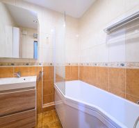 Badezimmer mit Badewanne und Waschbecken in einer 3-Zimmer-Wohnung mit Fliesen und Spiegel.