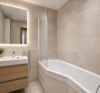 Badezimmer in einer 3-Zimmer-Wohnung mit Badewanne, Waschbecken und Boden mit Holzdekor.