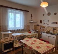 Küche in einem Einfamilienhaus mit Mikrowelle, Herd, Tisch und Spüle.