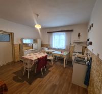 Eine Küche in einem Einfamilienhaus mit einem Boden in Holzoptik, einfache Möbel und ein Esstisch.