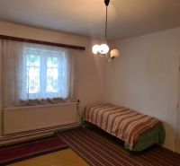 Einfaches Zimmer mit Bett und Fenster, Einfamilienhaus, Teppich und Vorhänge.