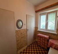 Ein Innenraum in einem Einfamilienhaus mit gefliestem Boden und einem Fenster mit Jalousien.