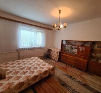 Ein Zimmer mit ausziehbarem Sofa, älterer Vitrine und Vorhang, in einem Einfamilienhaus.