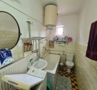 Badezimmer mit Spiegel, Waschbecken, Badewanne und Waschmaschine in einem Einfamilienhaus.