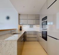 Küche in einer 3-Zimmer-Wohnung mit glänzenden Schränken und einem Boden in Holzoptik.