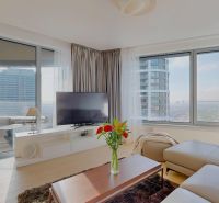 Helles Wohnzimmer mit Holzboden, Ecksofa und Fernseher.