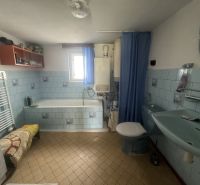 Ein Badezimmer in einem Einfamilienhaus mit blauen Fliesen und einer Badewanne.