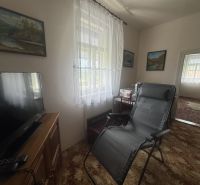 Wohnzimmer in einem Einfamilienhaus mit Fernseher, Sessel und Wanddekorationen.
