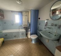 Ein Badezimmer in einem Einfamilienhaus mit blauen Fliesen und einer Badewanne.