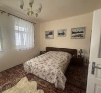 Schlafzimmer im Einfamilienhaus mit Bett, Teppich und Vorhängen an den Fenstern.