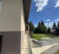 Ein Einfamilienhaus in Orlové mit einem Gehweg und Grünflächen, umgeben von Bäumen und blauem Himmel.