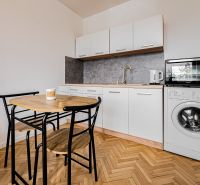 Einzimmerwohnung mit Küchenzeile und Geräten, Boden mit Holzdekor, Esstisch und Stühle.