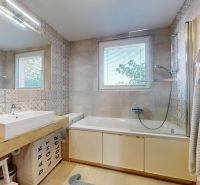 Badezimmer mit Badewanne, Waschbecken, dekorativen Fliesen und Fenster in einer 3-Zimmer-Wohnung.