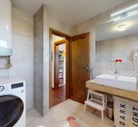 Badezimmer in einer 3-Zimmer-Wohnung mit Fliesen, Waschbecken und Waschmaschine mit Stauraum.