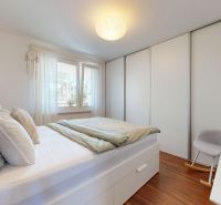 Schlafzimmer mit Bett, Einbauschrank und Boden mit Holzdekor in einer 3-Zimmer-Wohnung.