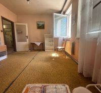 Wohnzimmer in einer Zweizimmerwohnung mit Teppich, offenem Fenster, Möbeln und Bildern.