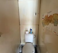 Eine enge Toilette mit einer Karte an der Wand in einer 3-Zimmer-Wohnung.