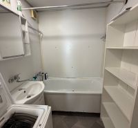 Badezimmer in einer 3-Zimmer-Wohnung mit Badewanne, Waschbecken, Waschmaschine und Regalschrank.