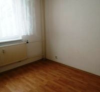 Ein Zimmer in einer 3-Zimmer-Wohnung mit einem Boden in Holzoptik, einem Vorhang und einem Heizkörper.