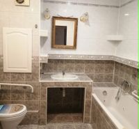 Badezimmer in einer 3-Zimmer-Wohnung mit Badewanne, Spiegel und Toilette, gefliest.
