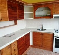 Küche in einer 3-Zimmer-Wohnung mit Holzschränken und weißer Arbeitsplatte.