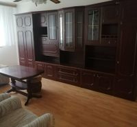 Wohnzimmer mit dunklen Holzmöbeln und Holzdekorboden in einer 3-Zimmer-Wohnung.