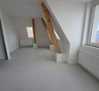 Dachgeschoss-Interieur in einer 2-Zimmer-Wohnung mit hellen Wänden und Balken.