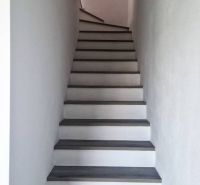 Eine Treppe mit einem Boden in Holzoptik, die in einem Einfamilienhaus nach oben führt.