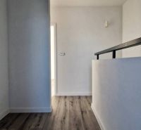 Ein Flur in einem Einfamilienhaus mit einem Boden in Holzoptik und weißen Wänden.