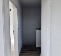 Ein Flur in einem Einfamilienhaus mit weißen Wänden und einem Boden in Holzoptik.