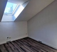Dachzimmer mit großem Dachfenster und Holzboden in einem Einfamilienhaus.