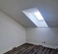 Dachzimmer mit Holzboden und Dachfenster in einem Einfamilienhaus.
