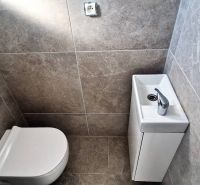 Toilette mit Waschbecken im Einfamilienhaus, graue Wandfliesen.