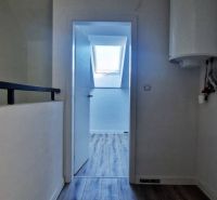 Flur in einem Einfamilienhaus mit Holzboden, im Hintergrund ein Dachfenster.