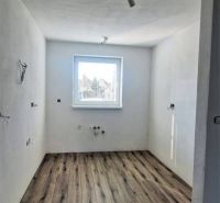 Ein Blick in einen Raum eines Einfamilienhauses mit einem Boden in Holzoptik und einem Fenster.