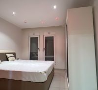 Schlafzimmer mit Doppelbett, weißen Wänden und Schrank, Besondere Immobilien.
