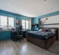 Schlafzimmer in einem Einfamilienhaus, blaue Wände, Bett, Schreibtisch und Boden mit Holzdekor.