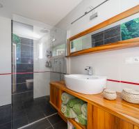 Badezimmer mit großzügiger Duschkabine und Holzschrank in einem Einfamilienhaus.