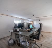 Ein Büroraum in einem Einfamilienhaus mit einem Boden in Holzoptik und Schreibtischen.