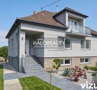 Ein Einfamilienhaus in Dolné Saliby mit einem gepflegten Garten und einem Steinsockel.