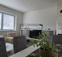 Wohnzimmer in einem Einfamilienhaus mit Kamin, Fernseher, Sitzgarnitur und Fenster mit Jalousien.