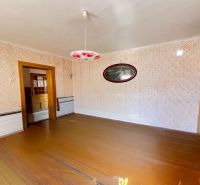 Ein Zimmer in einem Einfamilienhaus mit einem Holzboden und gemusterten Wänden.