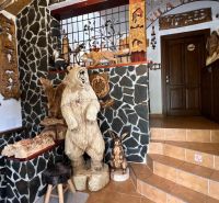Interieur der Villa mit hölzernen Tierskulpturen und Steinwänden.