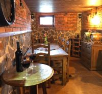 Weinkeller mit Backsteinwänden und Holztisch in einer Villa, Wein auf dem Tisch.